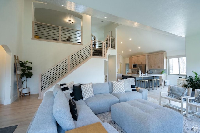 14661 S Rock Canyon Cir W, Herriman, UT 84096 - living area with stairs, recessed lighting, light wood-style flooring, arched walkways, and high vaulted ceiling