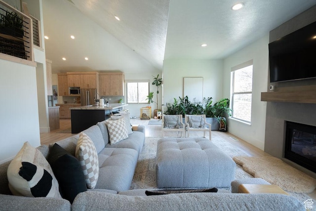 14661 S Rock Canyon Cir W, Herriman, UT 84096 - living area with plenty of natural light, a glass covered fireplace, light wood-style flooring, recessed lighting, and a towering ceiling