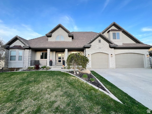 14661 S Rock Canyon Cir W, Herriman, UT 84096 - view of front of house with stone siding, stucco siding, a porch, driveway, and a front lawn