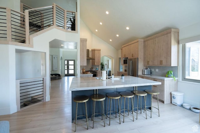 14661 S Rock Canyon Cir W, Herriman, UT 84096 - kitchen with light brown cabinets, appliances with stainless steel finishes, high vaulted ceiling, plenty of natural light, and light stone counters