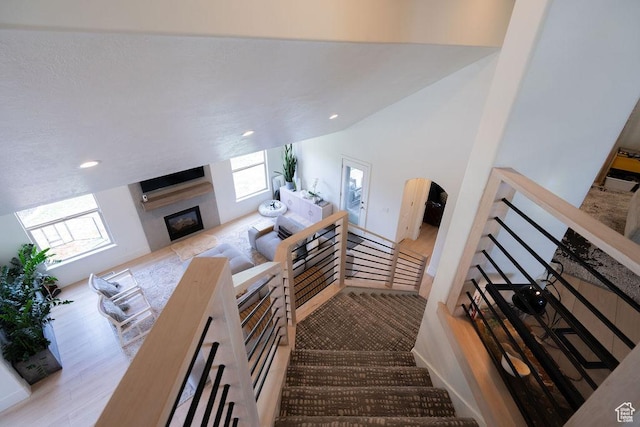 14661 S Rock Canyon Cir W, Herriman, UT 84096 - stairs with a glass covered fireplace, wood finished floors, recessed lighting, arched walkways, and vaulted ceiling