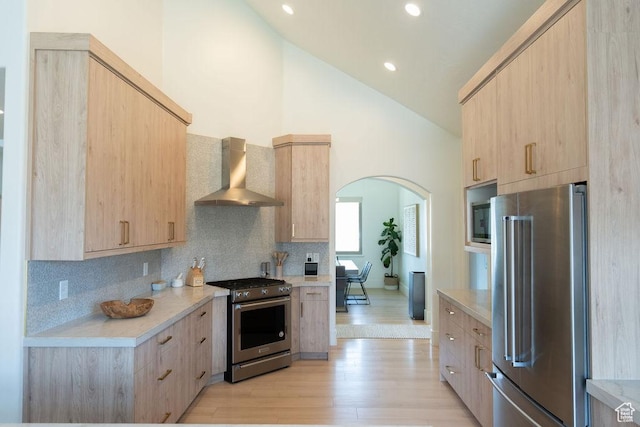 14661 S Rock Canyon Cir W, Herriman, UT 84096 - kitchen with appliances with stainless steel finishes, wall chimney exhaust hood, light brown cabinets, light countertops, and arched walkways