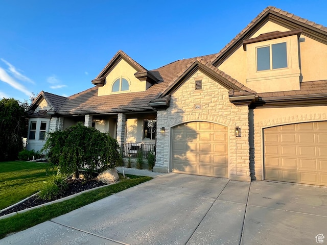 14661 S Rock Canyon Cir W, Herriman, UT 84096 - view of front of home with stone siding, driveway, stucco siding, covered porch, and a garage