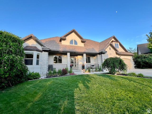 14661 S Rock Canyon Cir W, Herriman, UT 84096 - view of front of home featuring stone siding, covered porch, a front lawn, stucco siding, and a garage