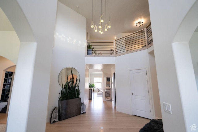 14661 S Rock Canyon Cir W, Herriman, UT 84096 - hallway with light wood-style floors, a towering ceiling, arched walkways, and a chandelier