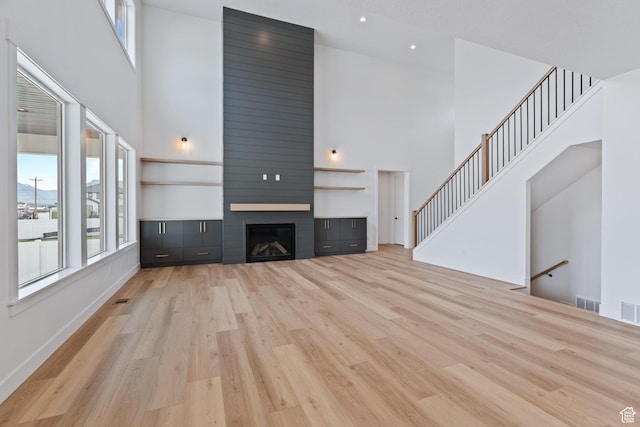 3010 W Willow Dr S, Lehi, UT 84043 - unfurnished living room with a fireplace, a healthy amount of sunlight, light wood finished floors, and a towering ceiling