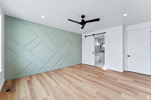 3010 W Willow Dr S, Lehi, UT 84043 - unfurnished bedroom featuring baseboards, a barn door, light wood-style flooring, and a decorative wall
