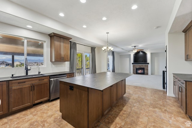 kitchen featuring stainless steel dishwasher, dark countertops, a sink, a tile fireplace, and a kitchen island