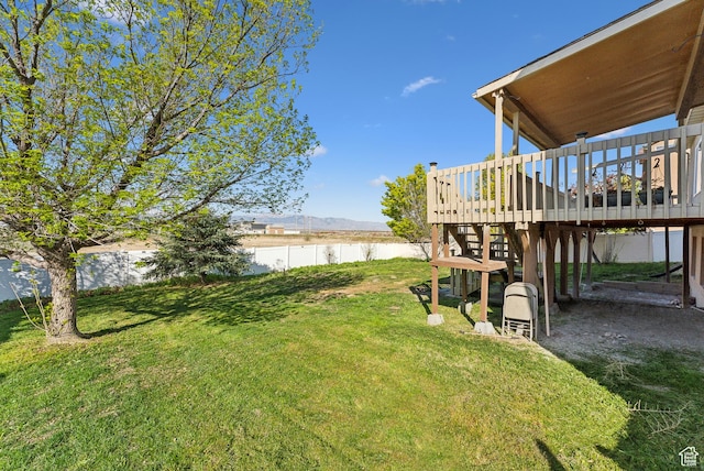 view of yard featuring a deck with water view and a fenced backyard