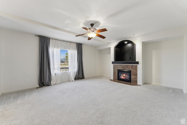 unfurnished living room with a tile fireplace, baseboards, carpet, and a ceiling fan