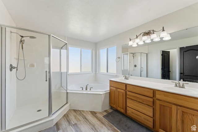 full bath featuring a shower stall, a garden tub, wood finished floors, a sink, and double vanity