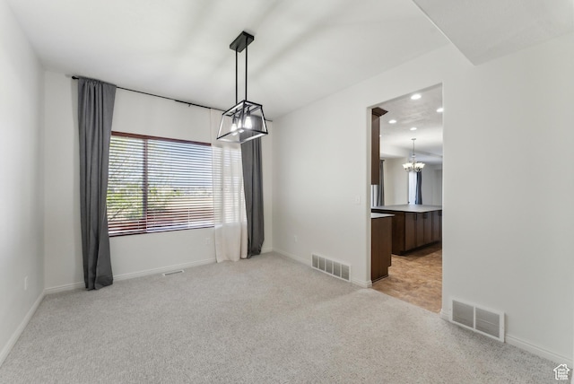 unfurnished dining area featuring light carpet, visible vents, and a notable chandelier