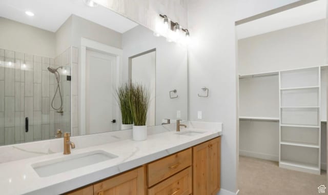 bathroom with a shower stall, a sink, a spacious closet, and double vanity