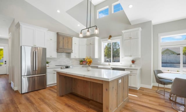 kitchen featuring white cabinets, decorative backsplash, stainless steel refrigerator, and light countertops