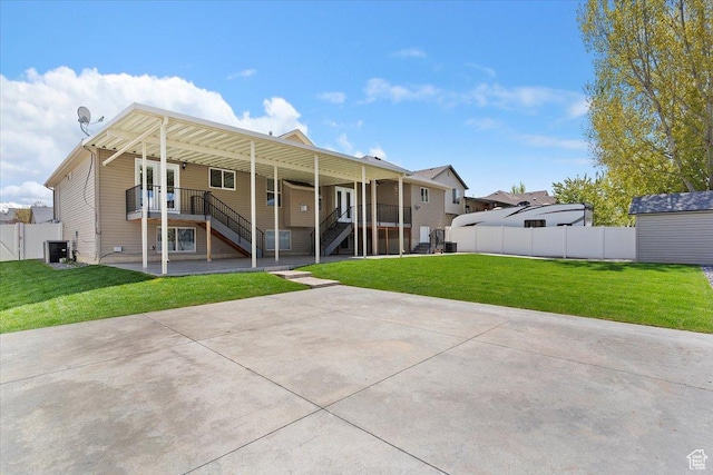 back of property with fence, a patio area, a lawn, and stairway