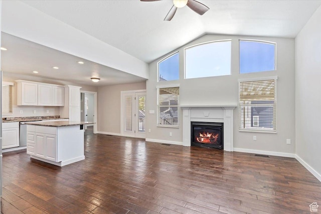 unfurnished living room with a glass covered fireplace, dark wood finished floors, and a ceiling fan