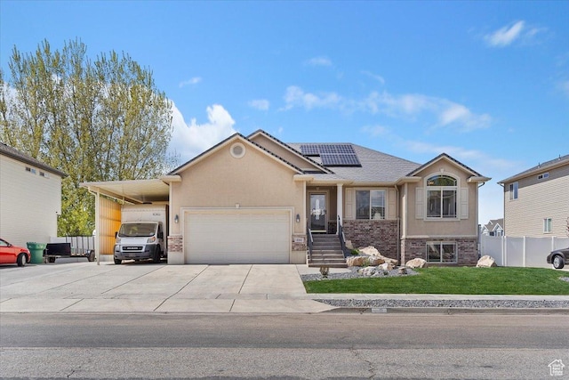 ranch-style home featuring concrete driveway, an attached garage, a front yard, stucco siding, and solar panels