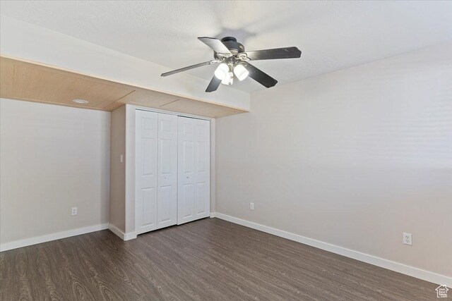 unfurnished bedroom with a ceiling fan, baseboards, dark wood-style flooring, and a closet