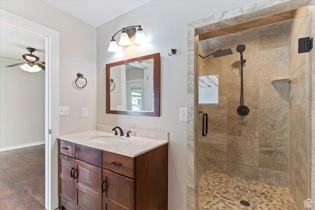 bathroom featuring baseboards, a ceiling fan, vanity, and a shower stall