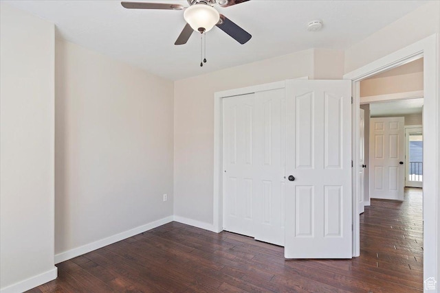unfurnished bedroom featuring a ceiling fan, baseboards, dark wood-style flooring, and a closet