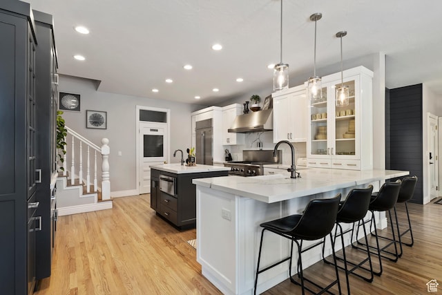 468 E 12000 S, Draper, UT 84020 - kitchen featuring stainless steel appliances, a peninsula, a kitchen island with sink, a sink, and wall chimney range hood