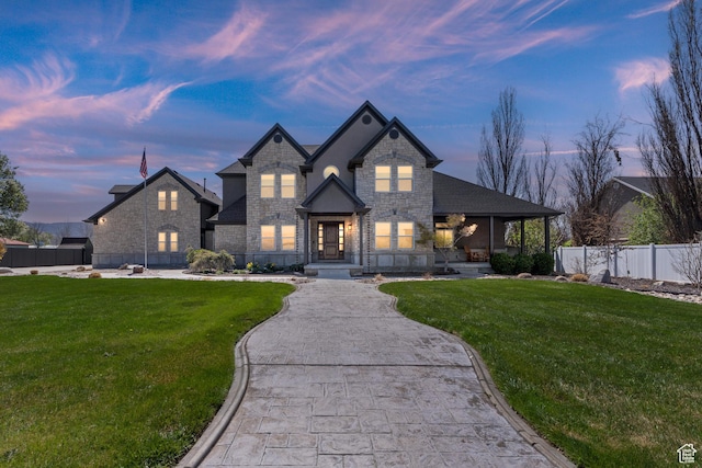 view of front of home featuring stone siding, a lawn, and fence