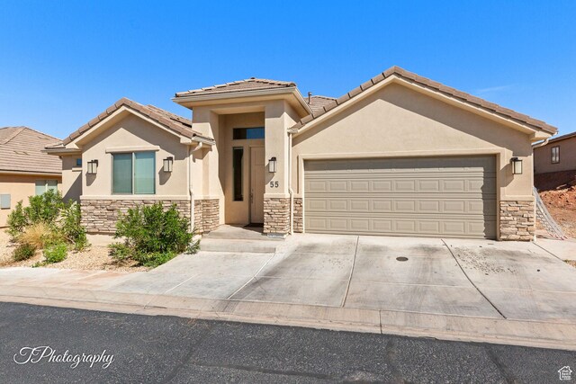 2261 S Tonaquint Dr W Unit 55, St George, UT 84770 - view of front of property with concrete driveway, an attached garage, stone siding, and stucco siding