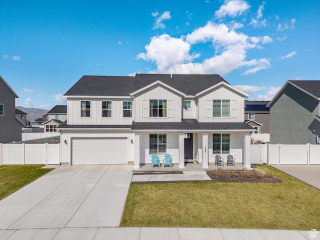 traditional-style home with driveway, a porch, an attached garage, board and batten siding, and a front yard