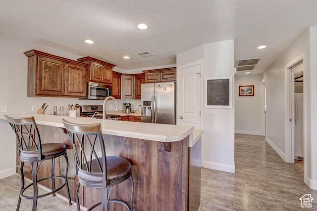 715 S Peachtree Dr, Toquerville, UT 84774 - kitchen featuring appliances with stainless steel finishes, a kitchen breakfast bar, visible vents, and light countertops
