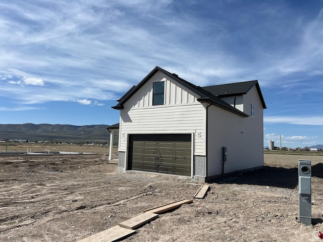 1155 E 1150 S, Garland, UT 84312 - view of property exterior with an attached garage, a mountain view, board and batten siding, and dirt driveway