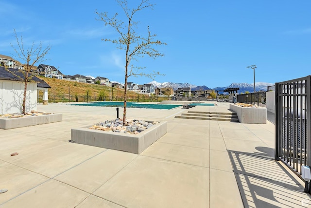 community pool with a patio area, fence, and a residential view