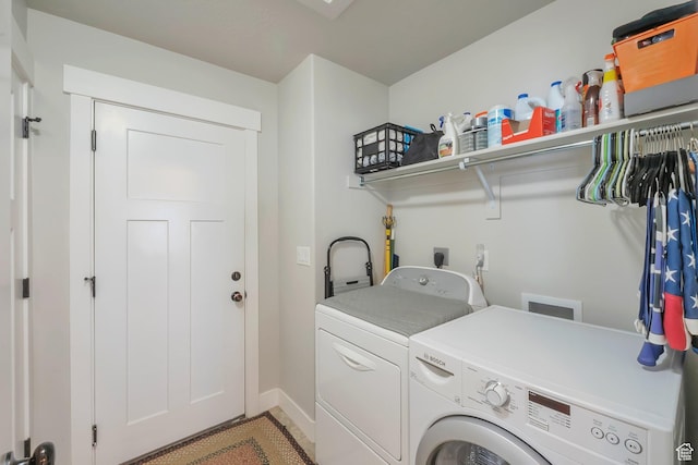 washroom with baseboards, washer and dryer, laundry area, and light tile patterned floors