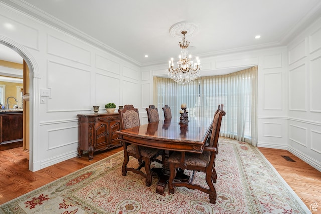 1230 E 11th Ave N, Salt Lake City, UT 84103 - dining space featuring a decorative wall, light wood-style flooring, a chandelier, arched walkways, and crown molding