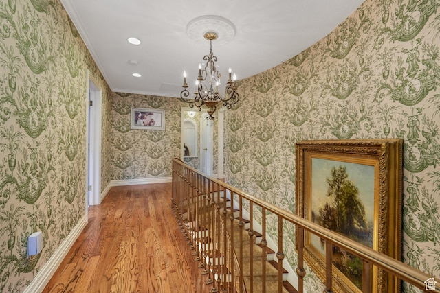 1230 E 11th Ave N, Salt Lake City, UT 84103 - hallway featuring wood finished floors, wallpapered walls, a chandelier, crown molding, and an upstairs landing