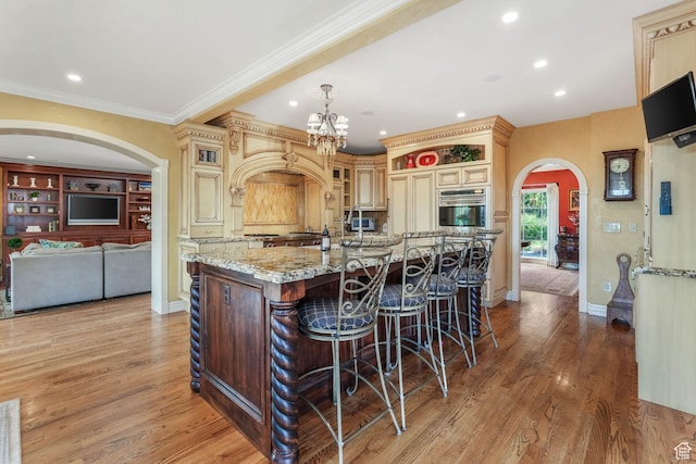 1230 E 11th Ave N, Salt Lake City, UT 84103 - kitchen with cream cabinets, stainless steel oven, arched walkways, and recessed lighting
