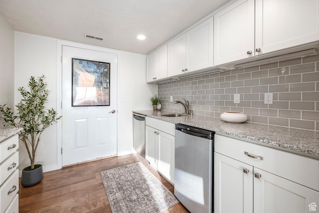 kitchen featuring dishwasher, light wood finished floors, a sink, and visible vents