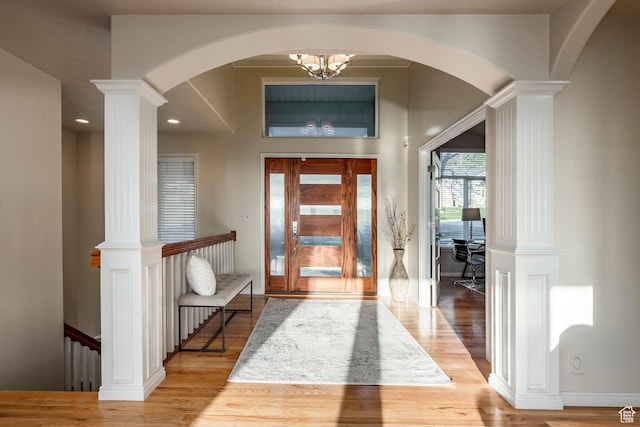 entryway featuring ornate columns, arched walkways, light wood finished floors, baseboards, and recessed lighting