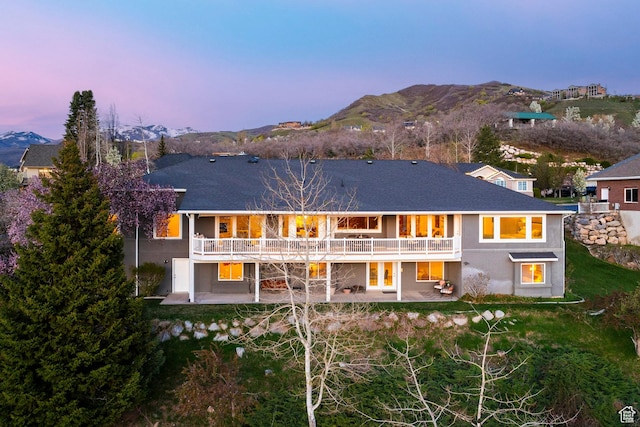 back of house at dusk with a patio, stucco siding, and a mountain view
