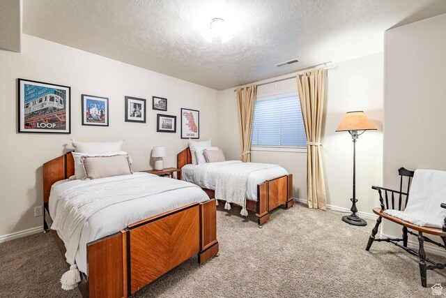 bedroom with a textured ceiling, baseboards, light carpet, and visible vents