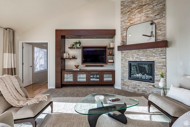 living room with baseboards, a stone fireplace, carpet, and high vaulted ceiling