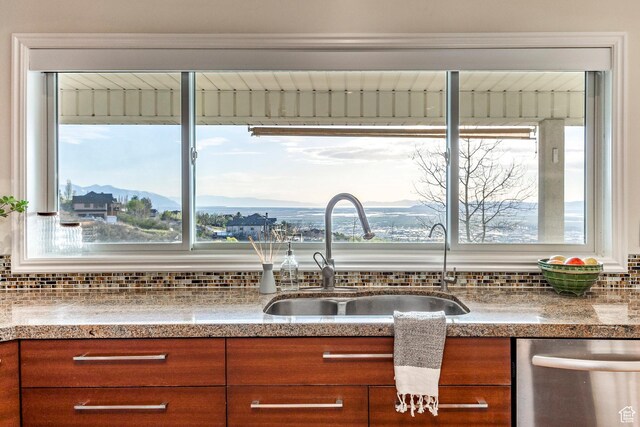 kitchen featuring a sink, decorative backsplash, brown cabinets, dishwasher, and a healthy amount of sunlight