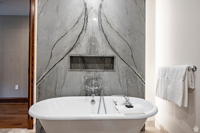 full bath with a soaking tub and baseboards