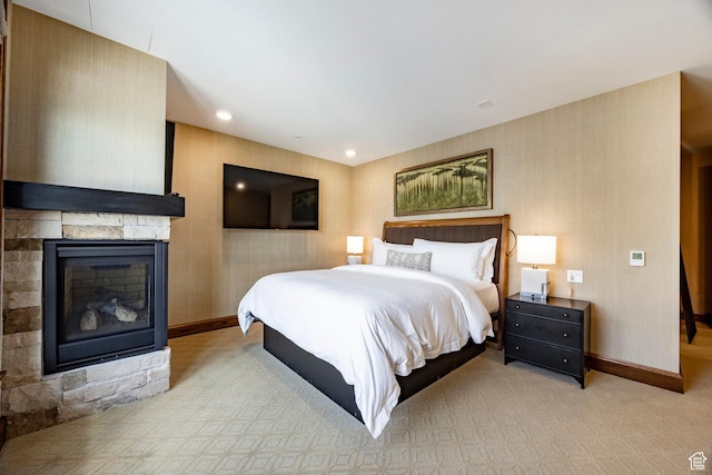 bedroom featuring light colored carpet, baseboards, a stone fireplace, and recessed lighting