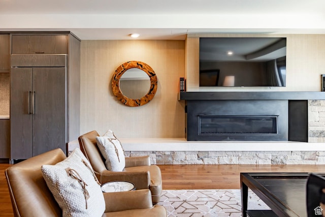 living room with recessed lighting, a stone fireplace, and wood finished floors