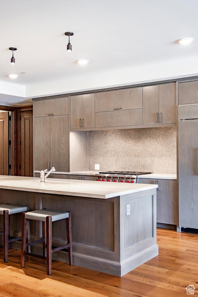 kitchen with a kitchen bar, backsplash, light countertops, and fridge
