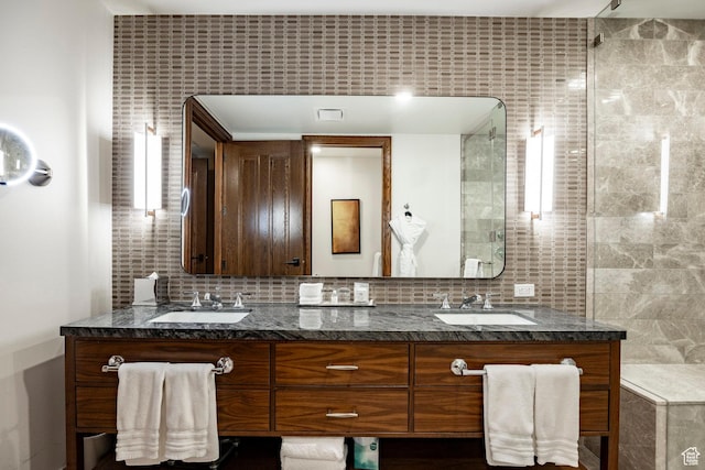 full bathroom featuring a tile shower, a sink, double vanity, and tile walls