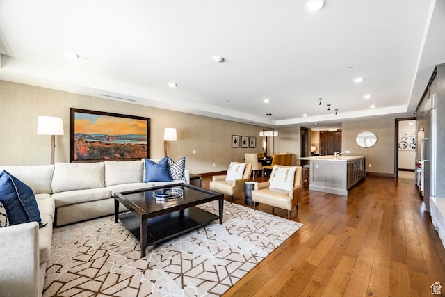 living room featuring recessed lighting, wallpapered walls, light wood finished floors, and a raised ceiling