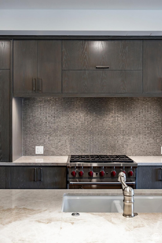 details with backsplash, high end range, dark brown cabinets, and a sink