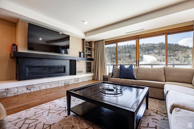 living room featuring built in shelves, recessed lighting, wood finished floors, and a fireplace