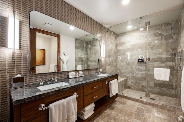 full bath with tile walls, a sink, a shower stall, and double vanity
